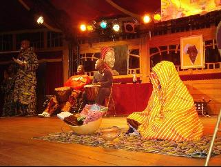 jeune fille habill�e en boubou traditionnel, la t�te recouverte d'un joli pagne (goro nyiraame) orn� aux bons soins du styliste, assise au milieu de la sc�ne et accompagn�e du traditionnel encens de mari�e (thiouraye)